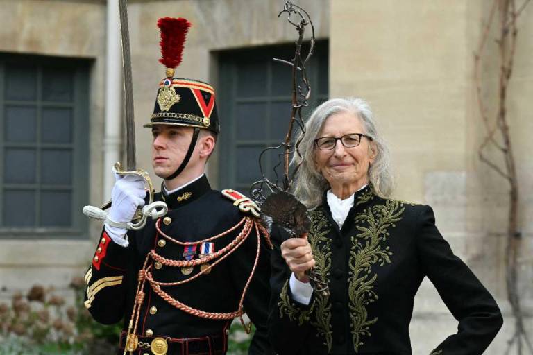 $!La fotógrafa estadounidense Annie Leibovitz (R) posa con su espada diseñada por Ariel Dearie después de su ceremonia de incorporación como miembro asociado extranjero de la Academia Francesa de Bellas Artes.