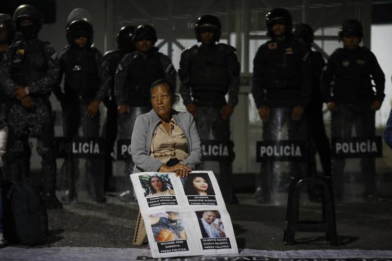 $!Una mujer sostiene fotografías de sus seres queridos mientras espera noticias sobre la liberación de presos.
