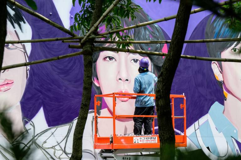 $!Un artista pinta con spray el mural de la banda K-pop BTS en Seúl que conmemora los 10 años de la banda.