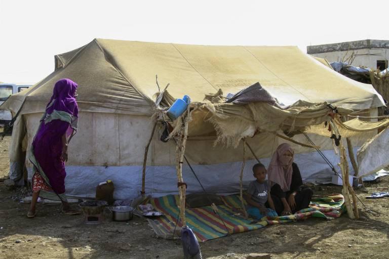 $!Una fotografía tomada el 20 de marzo de 2024 muestra a personas que huyeron de los estados de Jartum y Jazira en el Sudán devastado por la guerra, sentadas a la sombra de sus tiendas de campaña en un campamento para desplazados internos en el estado sureño de Gadaref.