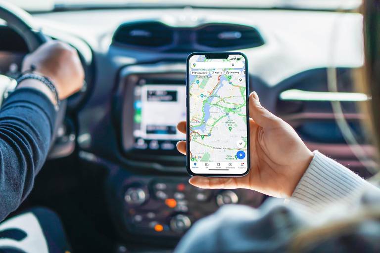 $!Una chica dentro de un auto sostiene un teléfono inteligente con la aplicación Google Maps en la pantalla.