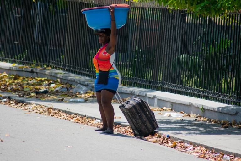 $!Una mujer sale de una zona incendiada por bandas armadas en Puerto Príncipe, Haití, el 25 de marzo de 2024.