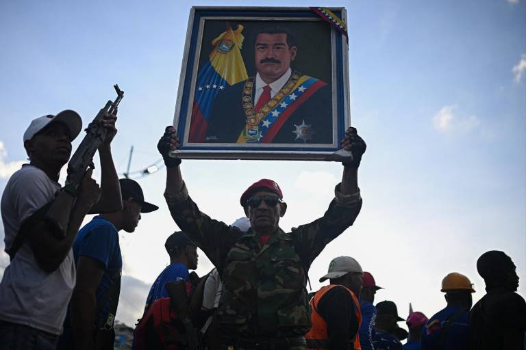 $!Un miembro de la milicia bolivariana sostiene una foto del presidente venezolano Nicolás Maduro junto a civiles armados durante un despliegue militar en apoyo a él en la Avenida Bolívar en Caracas.