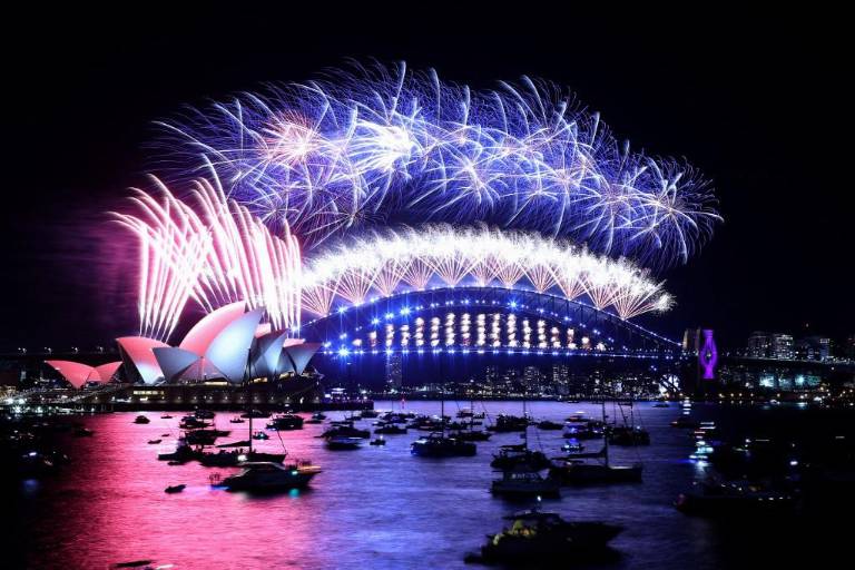 $!Los fuegos artificiales de Nochevieja iluminan el cielo sobre el icónico Harbour Bridge y la Ópera (izquierda) de Sydney durante el espectáculo de fuegos artificiales el 1 de enero de 2022.