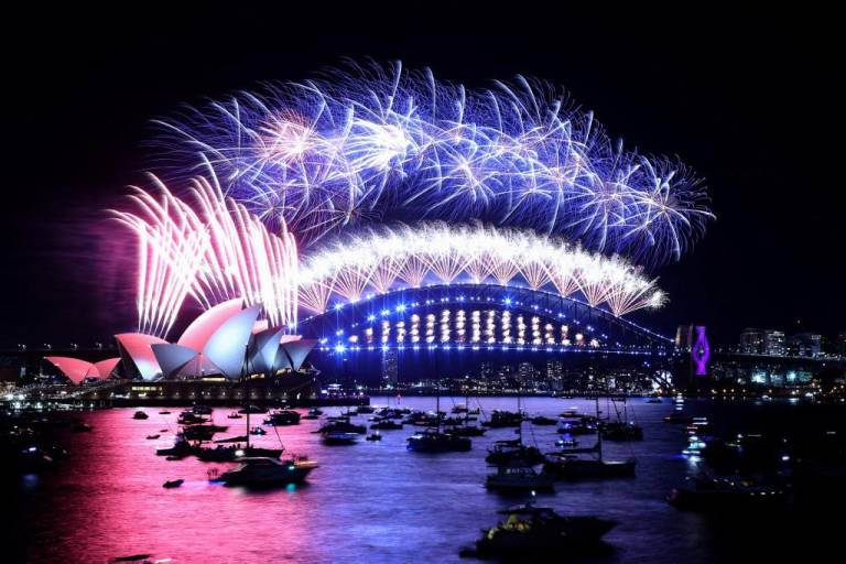 $!Los fuegos artificiales de Nochevieja iluminan el cielo sobre el icónico Harbour Bridge y la Ópera (izquierda) de Sydney durante el espectáculo de fuegos artificiales el 1 de enero de 2022.