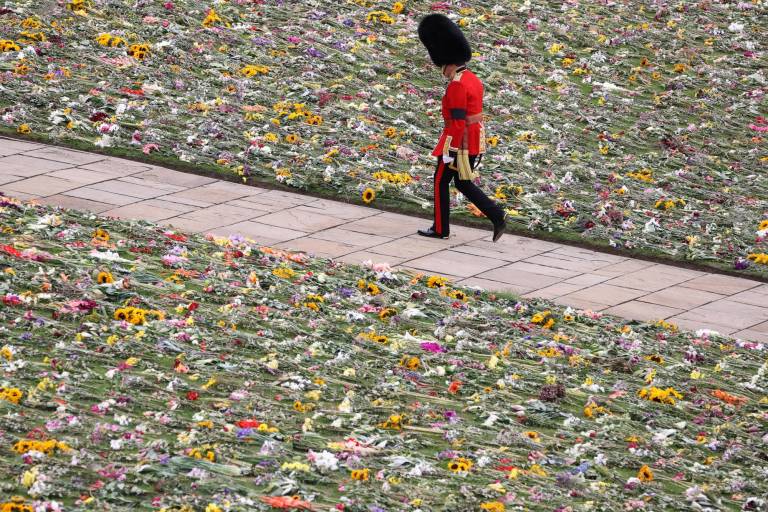 $!Un soldado de la guardia del rey camina por el Castillo de Windsor, cuyo cesped se cubrió de flores el día del funeral de la reina Isabel II.