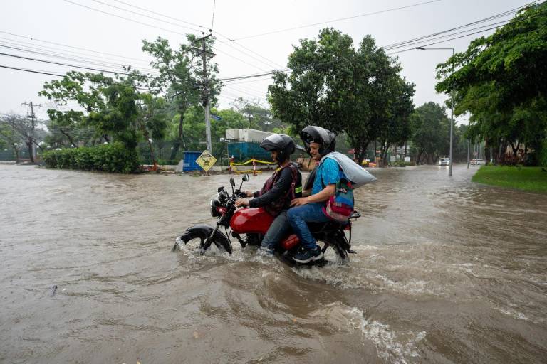 $!Motociclistas transitan por una calle inundada debido a las fuertes lluvias, este miércoles en Samborondón.