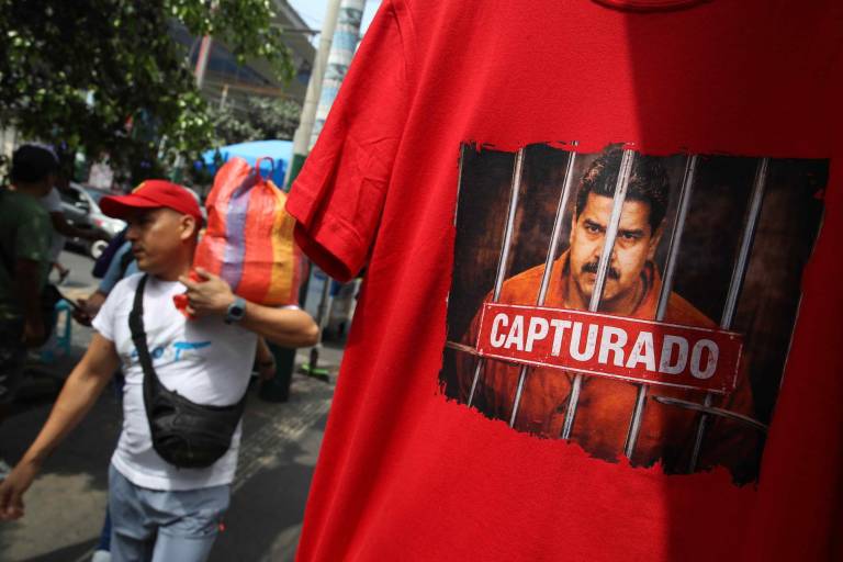 $!Un hombre camina frente a una camiseta con una imagen de la captura de Nicolás Maduro, este martes, en Lima (Perú).