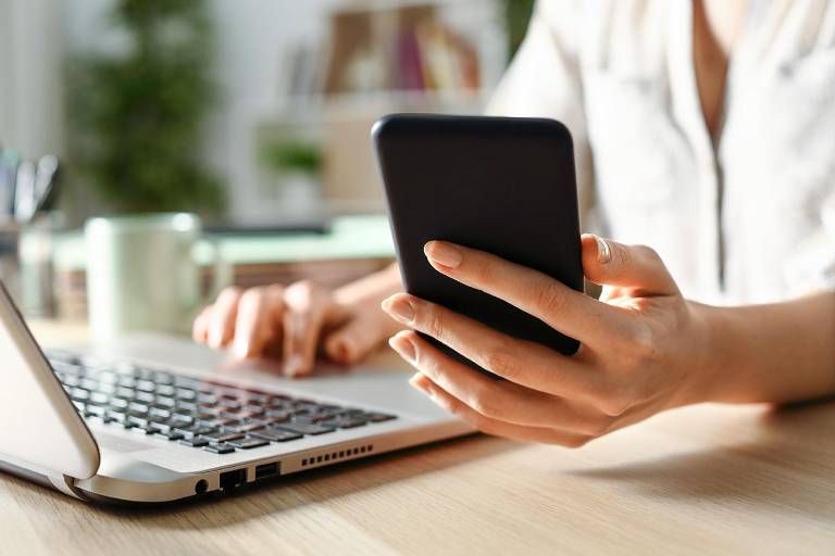 $!Mujer usando una computadora portátil y revisando su teléfono.