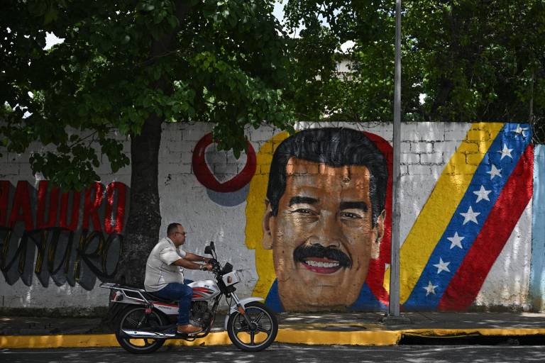 $!Un motociclista pasa junto a un mural que representa al presidente de Venezuela, Nicolás Maduro, en Caracas el 1 de septiembre de 2025.