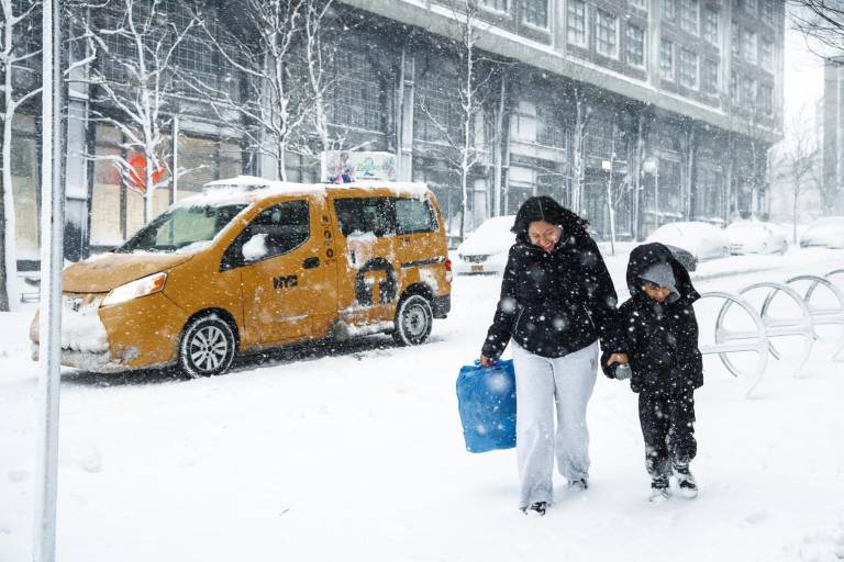 $!Una mujer junto a niño caminan mientras la tormenta en Nueva York.