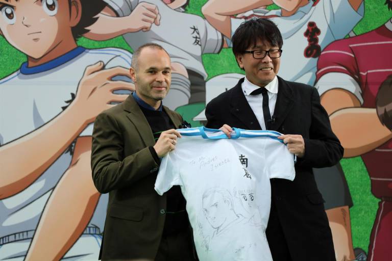 $!El futbolista español Andrés Iniesta (c), recibe una camiseta personalizada de manos del autor de Supercampeones, dedicada y con un dibujo suyo junto al protagonista de la serie, Oliver Atom