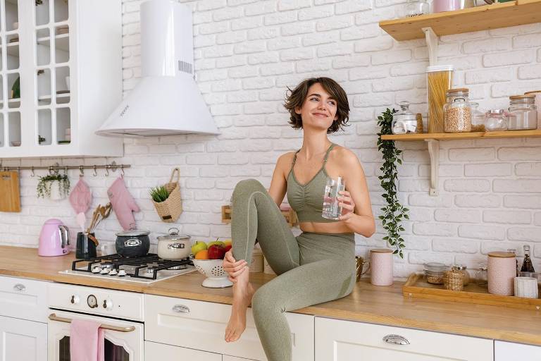 $!Mujer onriente en la cocina por la mañana bebiendo un vaso de agua.