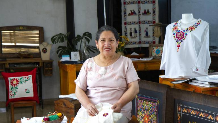 Teresa Casa Ponce, fundadora de Catelina, sentada junto a sus bordados dentro del taller donde capacita a quienes mantendrán la ancestral técnica.
