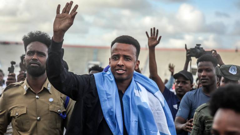El árbitro Omar Abdulkadir Artan saluda a sus seguidores envuelto en la bandera somalí durante la bienvenida previa a un partido de fútbol solidario tras su regreso a Somalia en Mogadiscio.