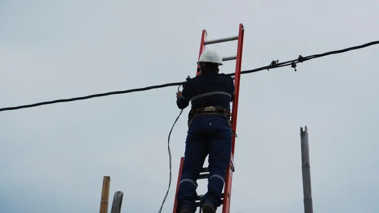 Colaborador de CNEL durante un trabajo de mantenimiento y cambio de cable, en una foto de archivo.