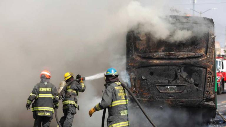 Integrantes del Cuerpo de Bomberos de Guadalajara intentan apagar un vehículo incendiado este domingo.