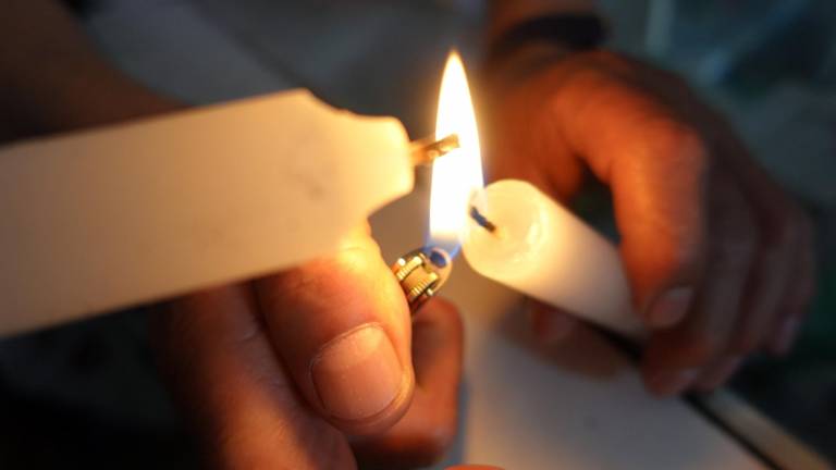 Personas prenden velas para iluminar sus hogares durante los apagones.