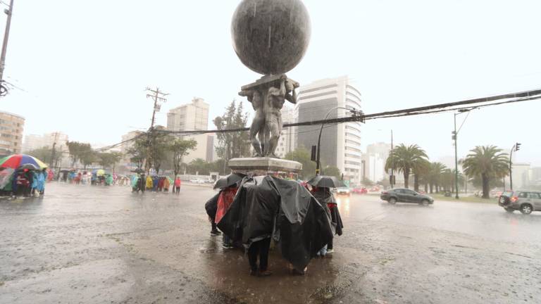 Personas se protegen de la lluvia en una zona del norte de Quito.