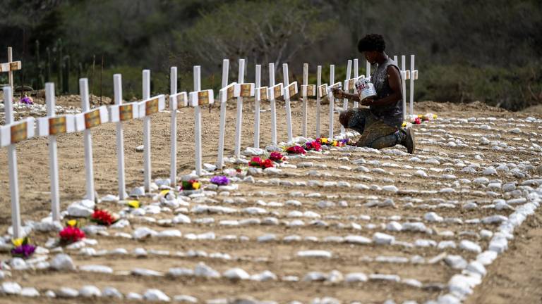A worker paints graves for unidentified victims of the June 24 earthquake at La Esperanza Cemetery in Catia La Mar, La Guaira state, northeast of Caracas, on July 5, 2026. Venezuela's devastating twin earthquakes killed nearly 3,000, updated official figures showed on July 4, as international rescue teams began winding down search operations for survivors in the rubble of the disaster. (Photo by Miguel MEDINA / AFP)
