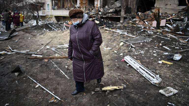 Una mujer camina frente a un edificio residencial dañado en la calle Koshytsa, un suburbio de la capital ucraniana, Kiev, donde supuestamente cayó un proyectil militar.