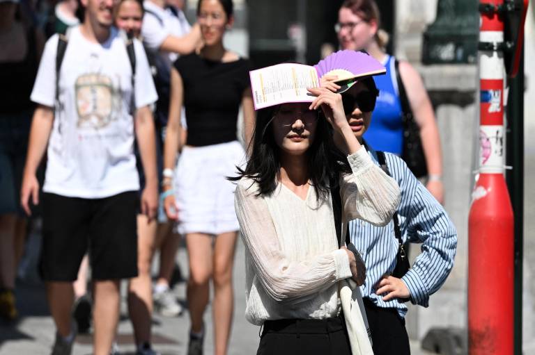 $!Los peatones se protegen del sol mientras caminan por las calles de Bruselas el 24 de junio de 2026, durante una ola de calor.