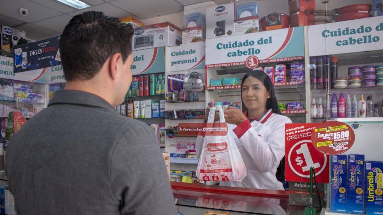 Colaboradora atiende a un cliente en una farmacia.