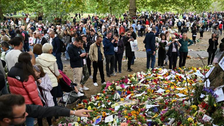 Personas miran las ofrendas de flores colocadas en Green Park, Londres, como tributo por el funeral de la reina Isabel II.