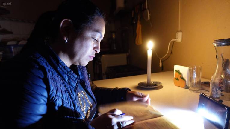 Ciudadana alumbra con velas y linternas para leer un libro.
