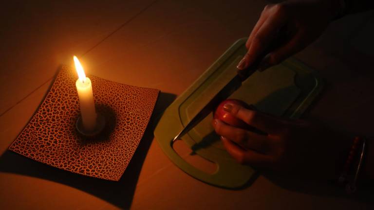 Una persona se alumbra con una vela durante uno de los cortes de energía programados.