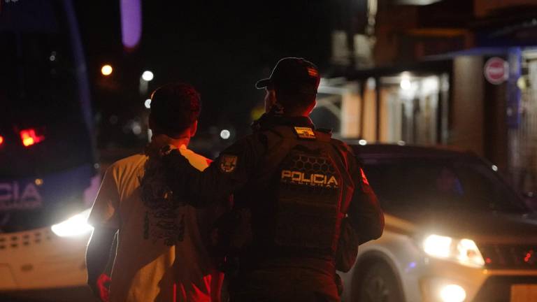 Un agente de Policía lleva a un ciudadano detenido hacia un vehículo de la institución, en el cantón de Durán, en la provincia de Guayas.