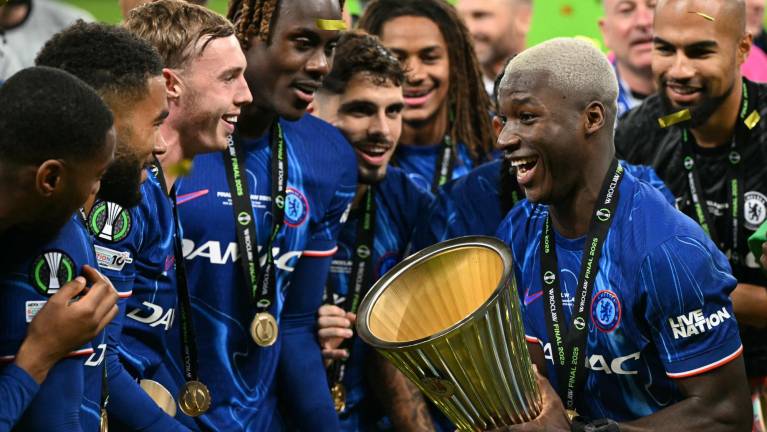 El mediocampista ecuatoriano #25 del Chelsea, Moisés Caicedo, sostiene el trofeo mientras los jugadores del Chelsea celebran.