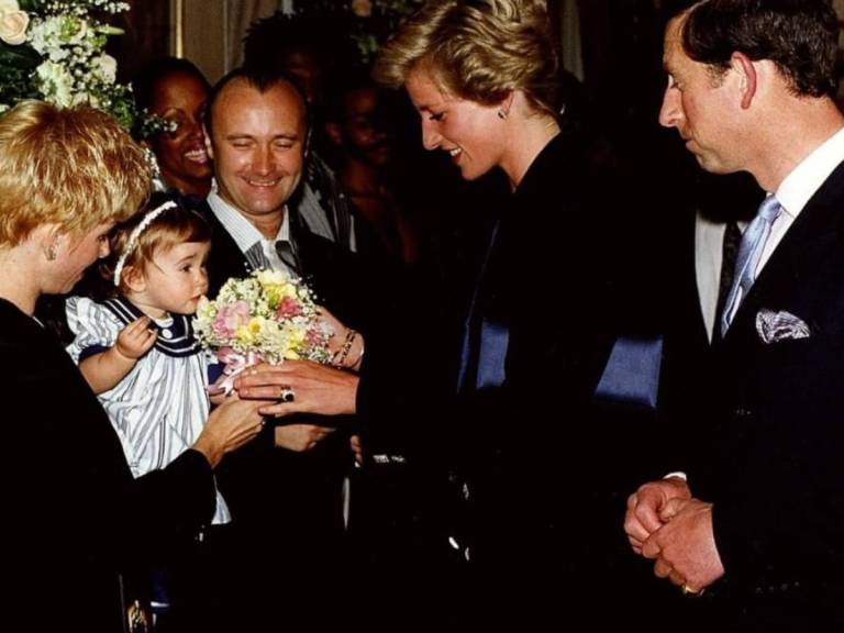 $!Foto en la que una pequeña Lily Collins trata de retener el ramo de flores, el cual es un regalo para Lady Di, la joven princesa sonríe, mientras pareciese que el príncipe Carlos también se divierte con la escena.