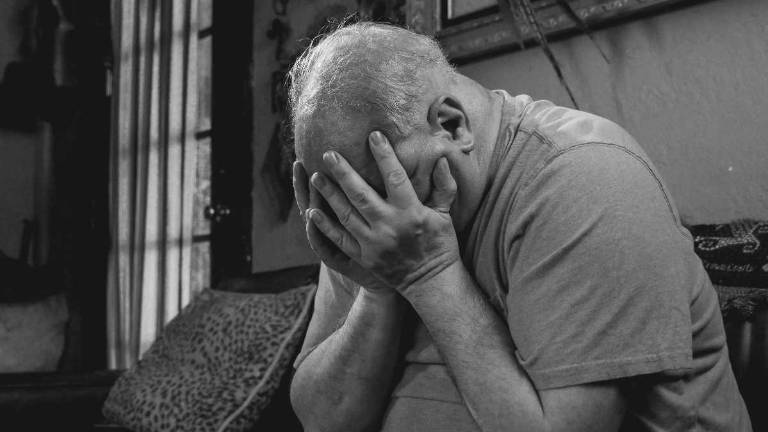 Adulto mayor solo consumido por la soledad y la depresión