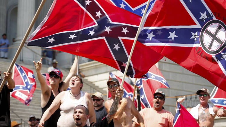 Miembros del Ku Klux Klan marcha con la bandera confederada