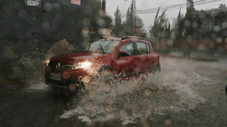 Fotografía referencial que muestra un auto atravesando un tramo inundado en la ciudad de Quito.