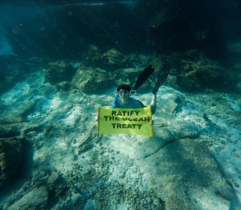 $!Fotografía cedida por Greenpeace que muestra a la actriz española Alba González mientras sostiene una pancarta que dice Ratificar el Tratado de los Océanos, mientras practica snorkel cerca de la isla Santiago, parte de las Islas Galápagos (Ecuador).