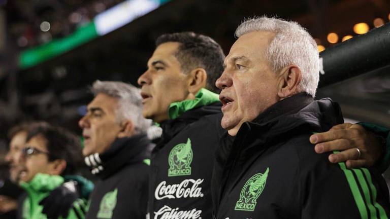 Javier Aguirre cantando el himno de México junto a su staff técnico.