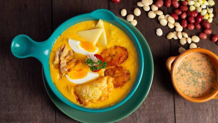 Un plato de fanesca servido con huevo, pescado, empanaditas, maduro y queso.