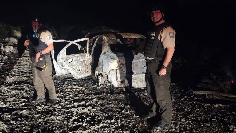 Fotografía que muestra a policías junto al vehículo incinerado que podría estar vinculado al asesinato de la magistrada.