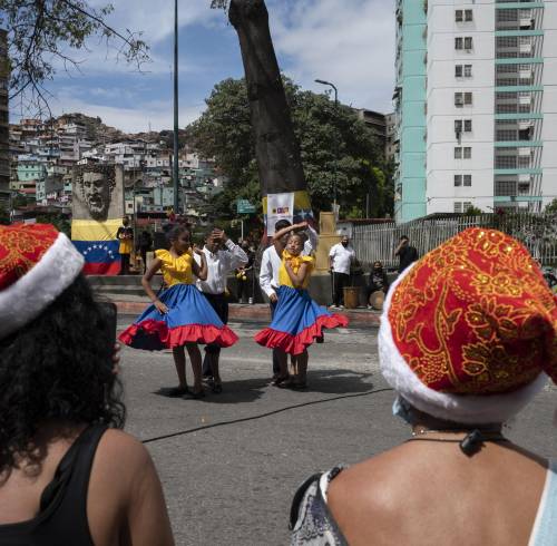 Unas mujeres llevan gorros navideños mientras observan a unos niños bailar en el barrio de El Valle (Caracas), el 1 de diciembre de 2021.