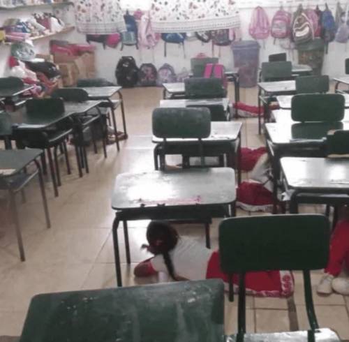 Imagen que muestra a estudiantes agachados bajo sus mesas durante el ataque armado.