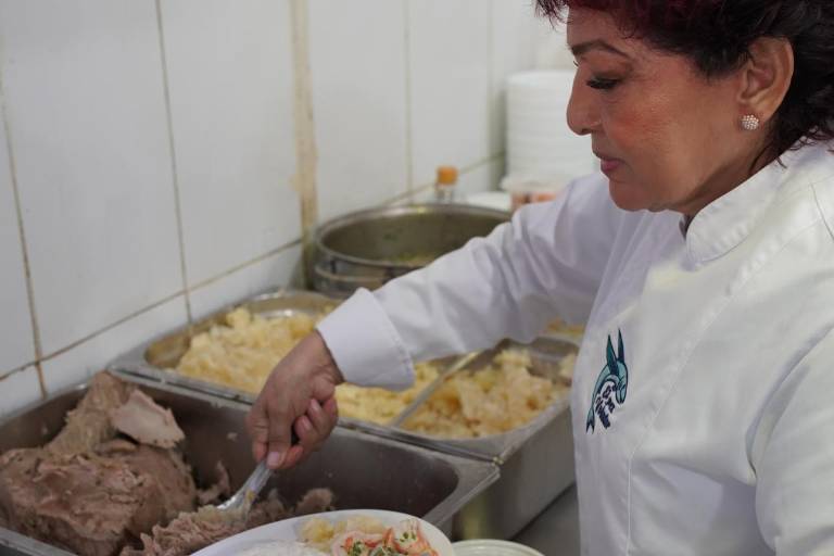 $!Angélica sirviendo un platillo denominado 'bandera'. En su menú hay humitas, bollos, cazuela, guatita, entre otros.