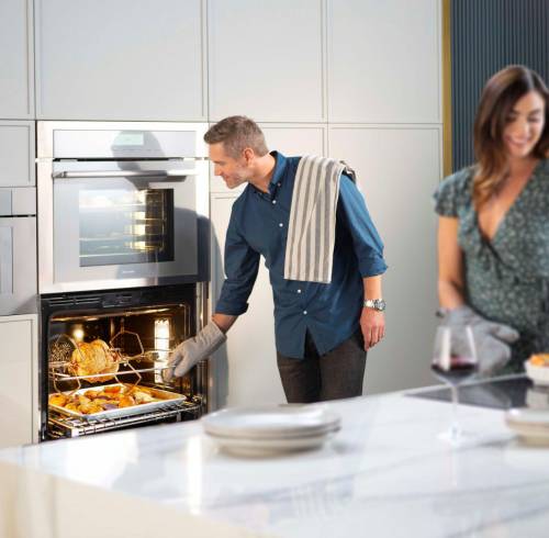 Un pareja prepara sus alimentos en una cocina implementada con elementos de lujo.