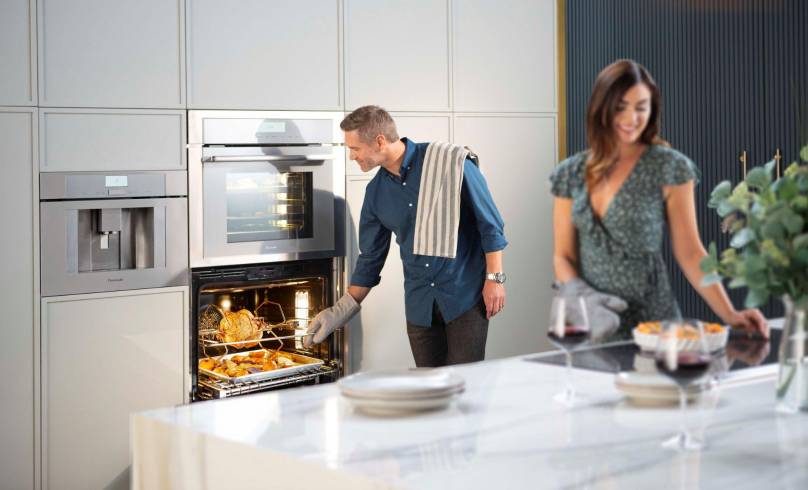 Un pareja prepara sus alimentos en una cocina implementada con elementos de lujo.