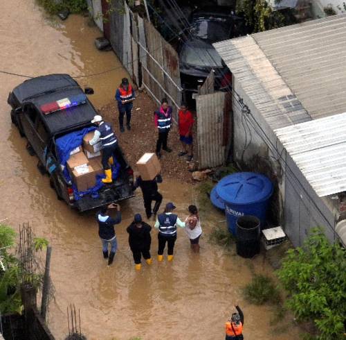 Fotografía que muestra a funcionarios del Gobierno entregando ayuda a una de las daminificadas por las lluvias en el cantón Durán.