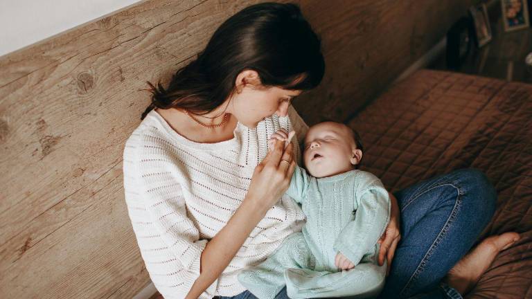 Foto una mamá cargando a su bebé en etapa de lactancia.