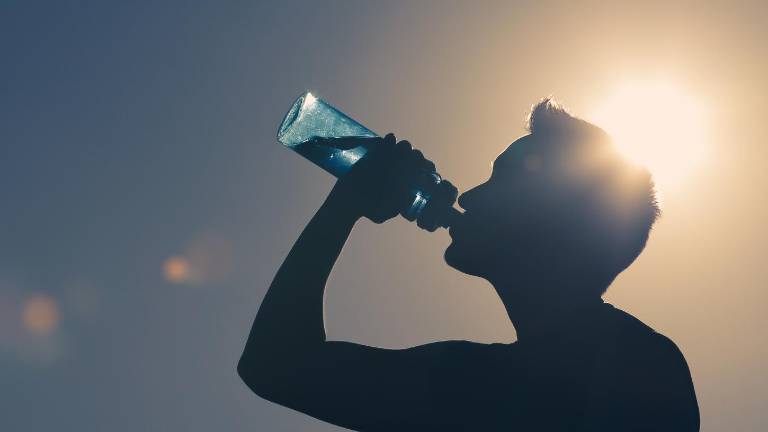 Persona hidratándose por el calor y humedad en Guayaquil.