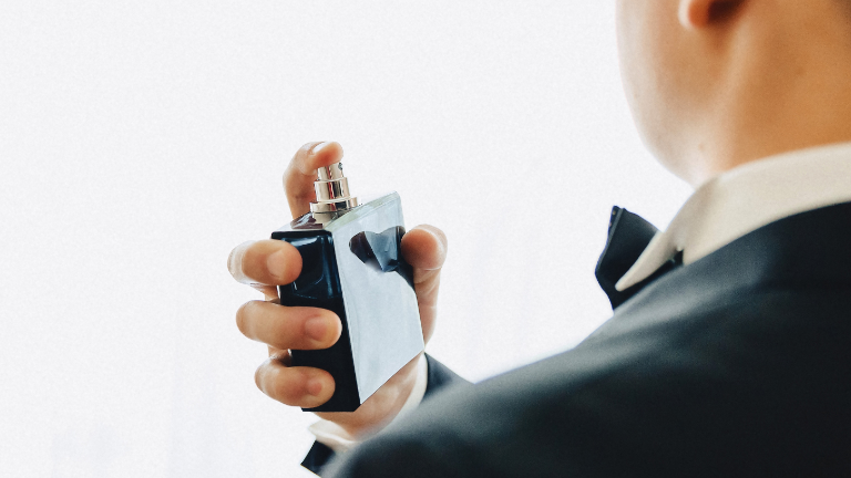 Imagen referencial de un hombre colocándose perfume. (Foto: Freepik.)