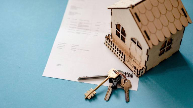 Casa modelo con llaves y documento.
